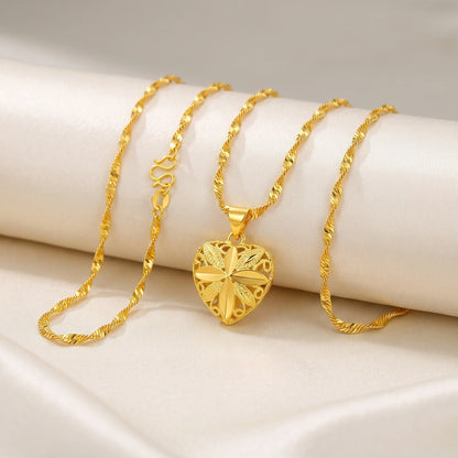 A gold heart-shaped pendant necklace with a twisted rope chain, displayed on a cream-colored satin fabric background.